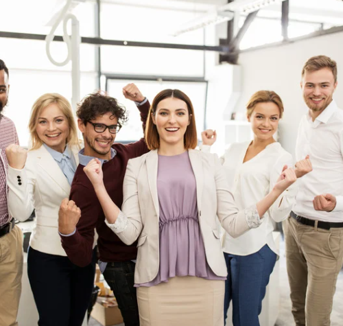 Group of professionals celebrating together with raised arms and smiling faces—symbolizing teamwork, achievement, and shared success.