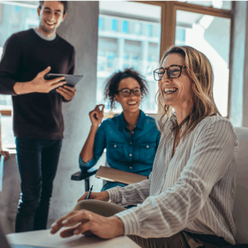 Group of professionals engaged in a lively brainstorming session around a table, with notes and laptops visible—representing creativity, teamwork, and problem-solving.